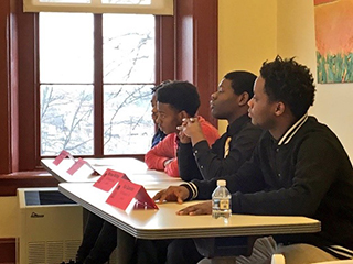 Four male students listening intently in a classroom
