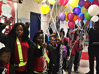 Students hold multi-colored balloons in the hallway. at their school.