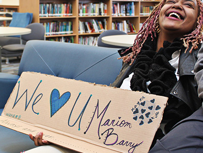 Woman holds a sign that reads We "Heart" U Marion Barry 