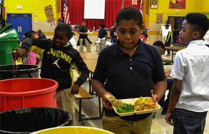 image of DCPS student sorting wastes into a red garbage can