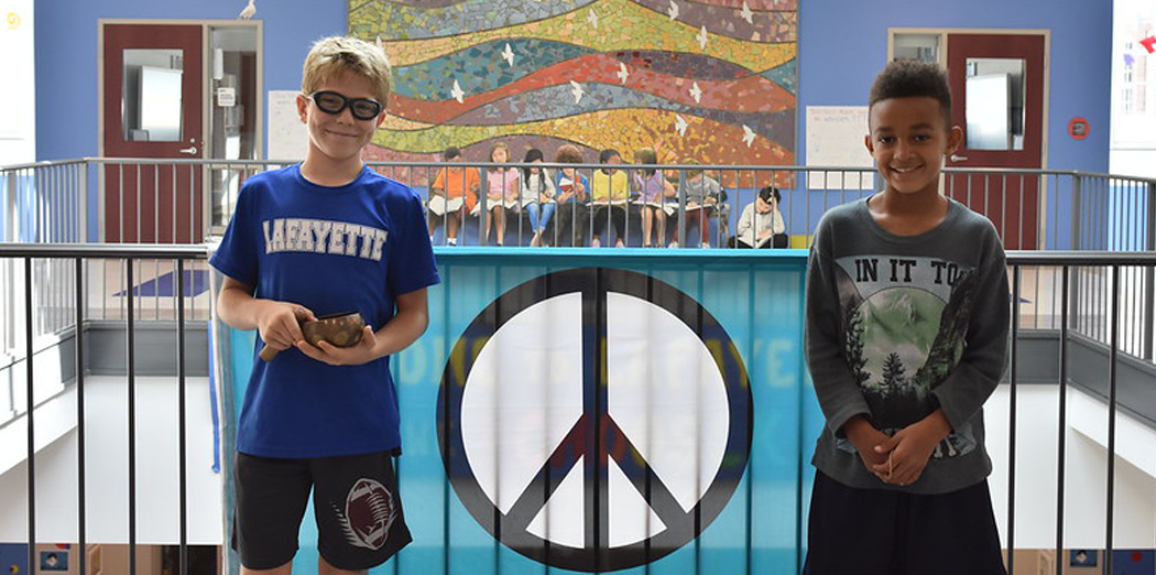 Two young boys standing in front a peace sign flag
