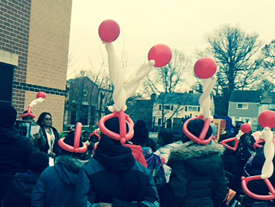 Students wear red and white balloon hats. 