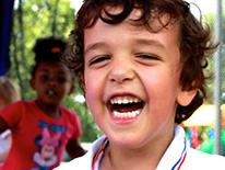 Photo of a smiling male pre-kindergarten student wearing a white shirt