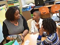 Photo of a woman speaking to two children in a classroom